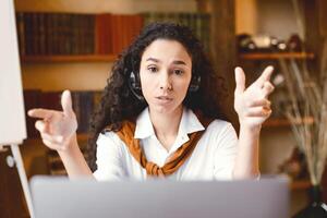 Remote Work. Portrait of focused woman sitting at desk, having call on laptop, explaining lesson to students or working and talking to colleagues and gesturing to webcam, consulting client photo