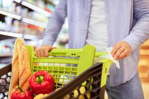 Stop Spreading Virus, Safety During Pandemic, Hygiene Concept. Closeup of man cleaning handle of shopping trolley cart, using antivirus antibacterial wet wipe napkin to protect himself from bacteria photo