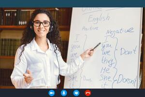 Distance Education And Technology. Woman In Glasses And Headset Having Conference, Teaching Foreign Languages, Talking To Camera During Web Call, Pointing At Whiteboard With Grammar Rules photo