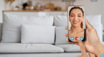 A person is using a smartphone to connect in a call, showcasing a casual home environment. The individual on the screen appears happy and focused on the conversation. photo
