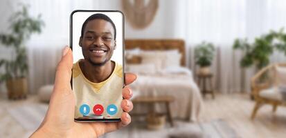 A person smiles on a call via smartphone, surrounded by soft lighting and decor, creating a warm and inviting atmosphere for comfortable communication. photo