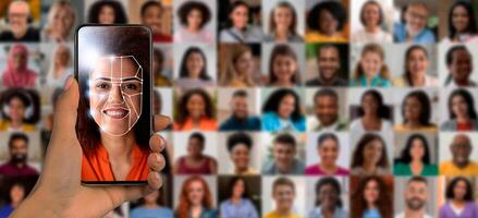 A hand holds a smartphone displaying facial recognition software. The screen shows a woman's face outlined for identification. photo