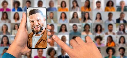 A user interacts with a smartphone, scanning their face for identification. Behind them, a collage features various diverse portraits illustrating modern facial recognition technology. photo