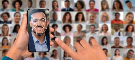 A hand holds a smartphone displaying a face recognition scan, with a collage of diverse faces in the background highlighting technological advancements in identification. photo