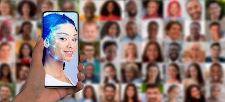 A person's hand holds a smartphone displaying facial recognition software. In the background, a collage of diverse faces represents modern identification technology and its impact on society today. photo
