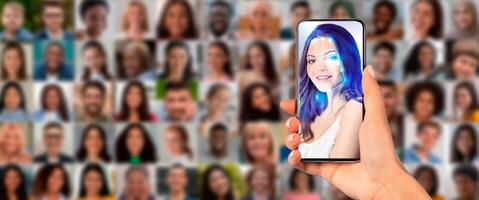 A hand holds a smartphone displaying a face scan in front of a collage of diverse portraits. This scene illustrates advanced identification technology in use today. photo