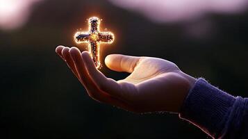 A glowing cross held in a hand against a blurred natural background during twilight photo