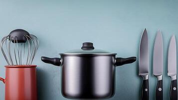 A modern kitchen scene featuring a pot, knives, and a whisk against a muted backdrop photo