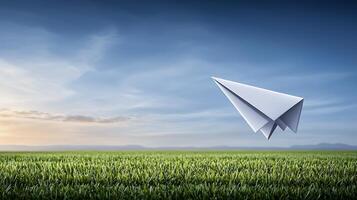 A paper airplane soaring over a green field at sunset, symbolizing freedom and creativity photo