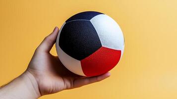 A person holding a colorful soccer ball against a vibrant yellow background photo