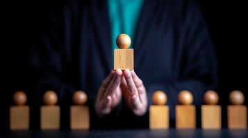 A person holding a wooden block with a sphere on top in a dark setting, symbolizing leadership and focus photo