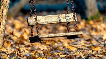 A rustic wooden swing hangs from chains, surrounded by vibrant autumn leaves in a serene forest photo