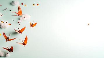 A serene scene of orange paper cranes flying through a light blue sky with soft clouds photo