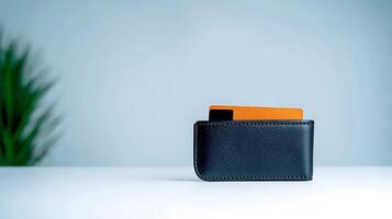 A sleek black wallet with an orange card partially visible against a soft blue background photo