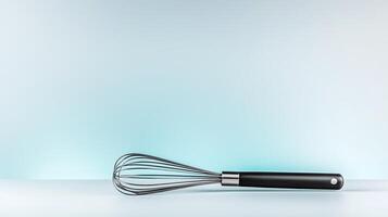 A sleek stainless steel whisk resting on a minimalist countertop with a soft blue gradient background photo