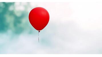 A solitary red balloon floats against a soft-focus background of blurred greenery photo