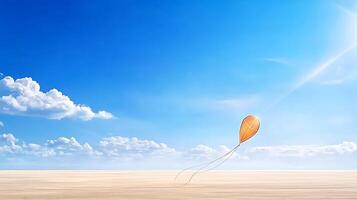 A vibrant orange kite soaring high in a clear blue sky over a serene sandy landscape photo