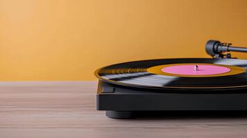 A vintage turntable playing a vinyl record with a pink label against a warm orange backdrop photo