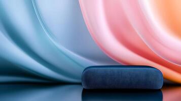 Abstract composition featuring a blue object against flowing pastel-colored fabric backdrop photo
