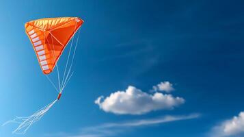 Bright orange kite soaring against a clear blue sky with fluffy white clouds in the background photo