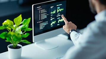 Business professional analyzing data on a computer screen with plant in office setting photo