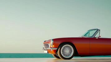 Classic convertible car parked by the ocean during sunset with a clear sky in the background photo