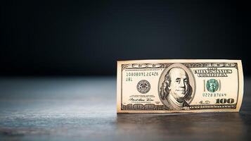 Close-up of a one hundred dollar bill resting on a wooden surface with a dark background photo