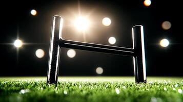 Close-up of a rugby goalpost on a vibrant green field under bright stadium lights at night photo