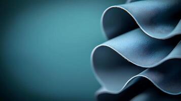 Close-up of elegant, wavy blue fabric folds against a soft teal background, showcasing texture photo