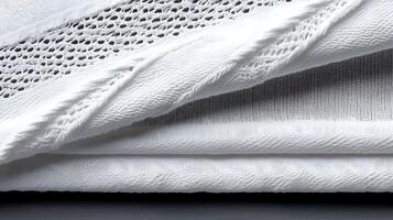Close-up of layered white fabrics showcasing texture and pattern variations on a dark surface photo