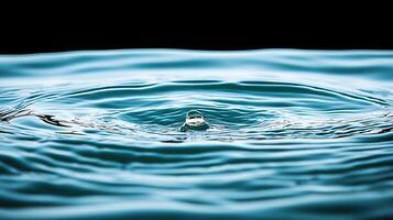 Close-up of water droplet creating ripples on a serene surface against a dark background photo