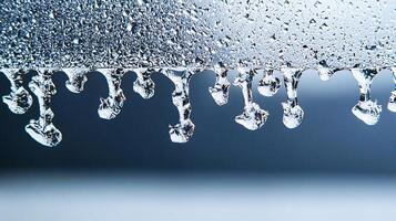 Close-up of water droplets forming and dripping from a metallic surface with a blurred background photo