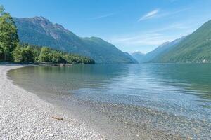A beach with clear water and mountains in the background photo