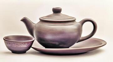 A ceramic teapot and cup on a white background photo