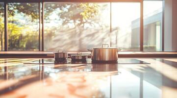 Modern kitchen countertop with stainless steel cookware. Sunlight streams through large windows photo