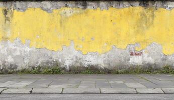Weathered yellow and gray wall, urban sidewalk photo