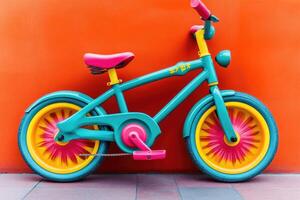 Vibrant kids' bicycle against a bold orange backdrop. Colorful teal, pink, and yellow design photo