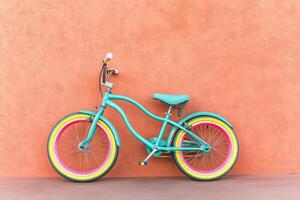 Teal child's bicycle against a peach wall photo