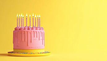 Pink birthday cake with candles on yellow background photo