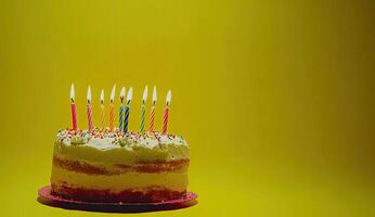 Birthday cake with colorful candles on a yellow background photo