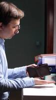 A man is looking at his wallet while sitting at a desk video