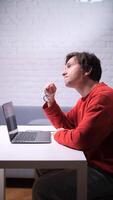 man is sitting at a table with a laptop video