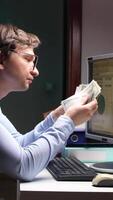 A man is looking at his computer screen while holding money video