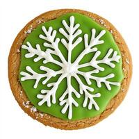 A cookie decorated with green icing and white snowflakes photo
