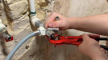 Hands of a Caucasian male using a wrench to fix plumbing pipes in a rustic setting, highlighting repair, maintenance, and DIY skills video