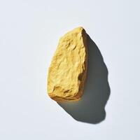 A yellow rock on a white surface photo