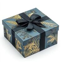 A gift box featuring a dark gray background with gold fern print. A black ribbon is tied in a bow on top photo