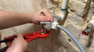 A person uses a wrench to fix plumbing in a rustic setting, highlighting DIY repair, home maintenance, and craftsmanship video