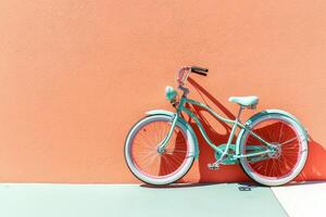 Mint green bicycle against coral wall photo