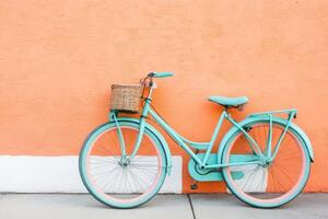 Teal bicycle with basket against coral wall photo